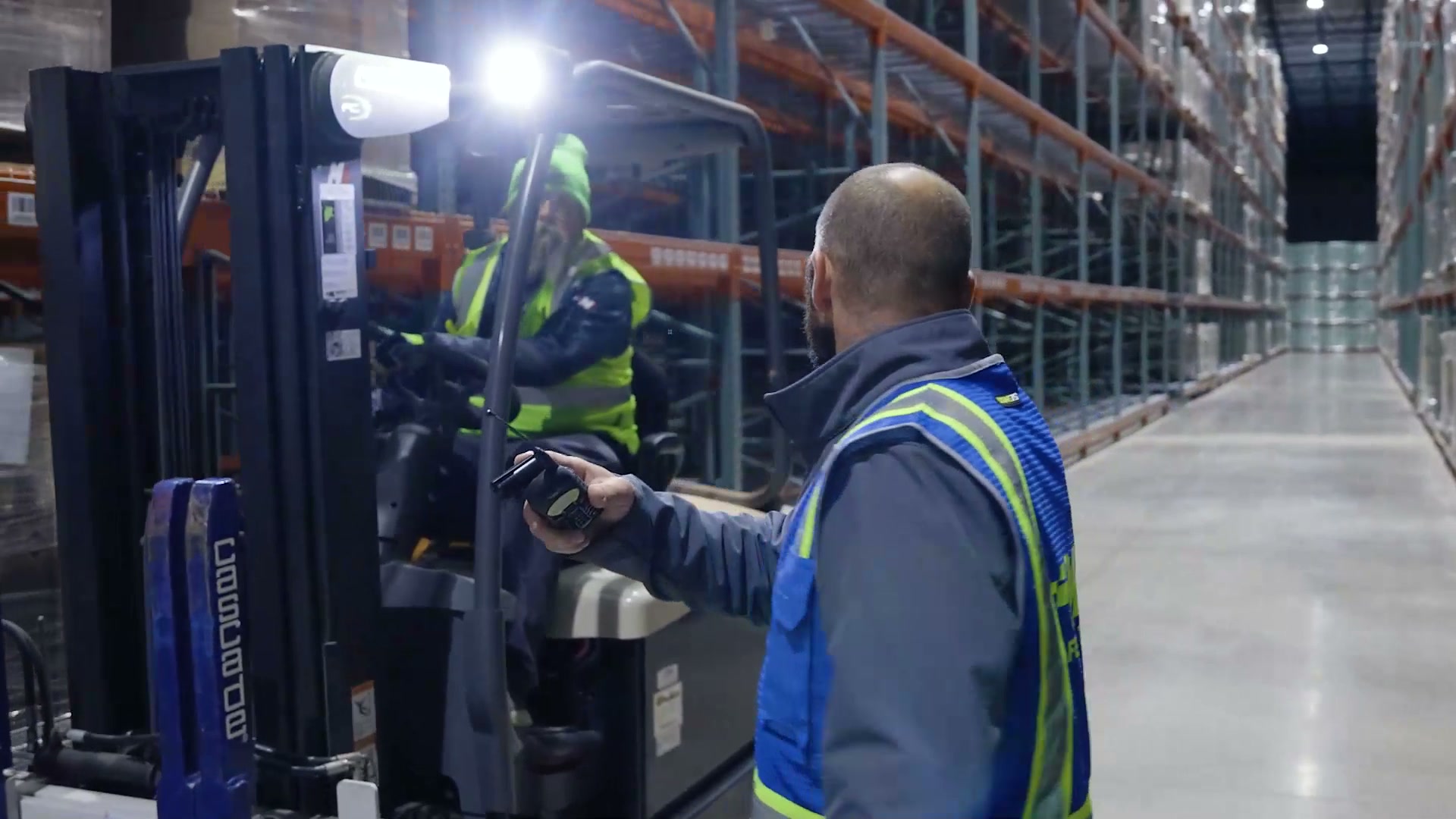A warehouse operator working beside a forklift
