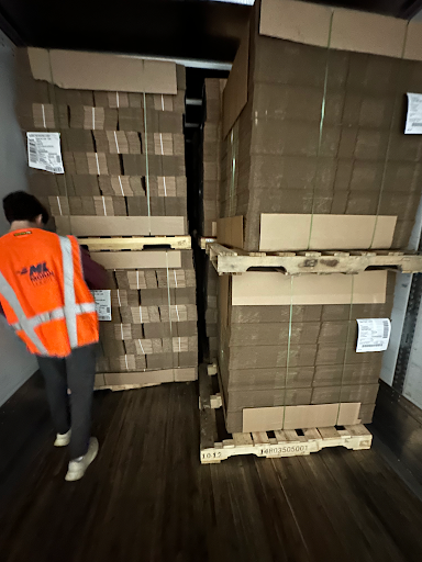 An operator in a hi-vis vest loading palletized cases inside a trailer