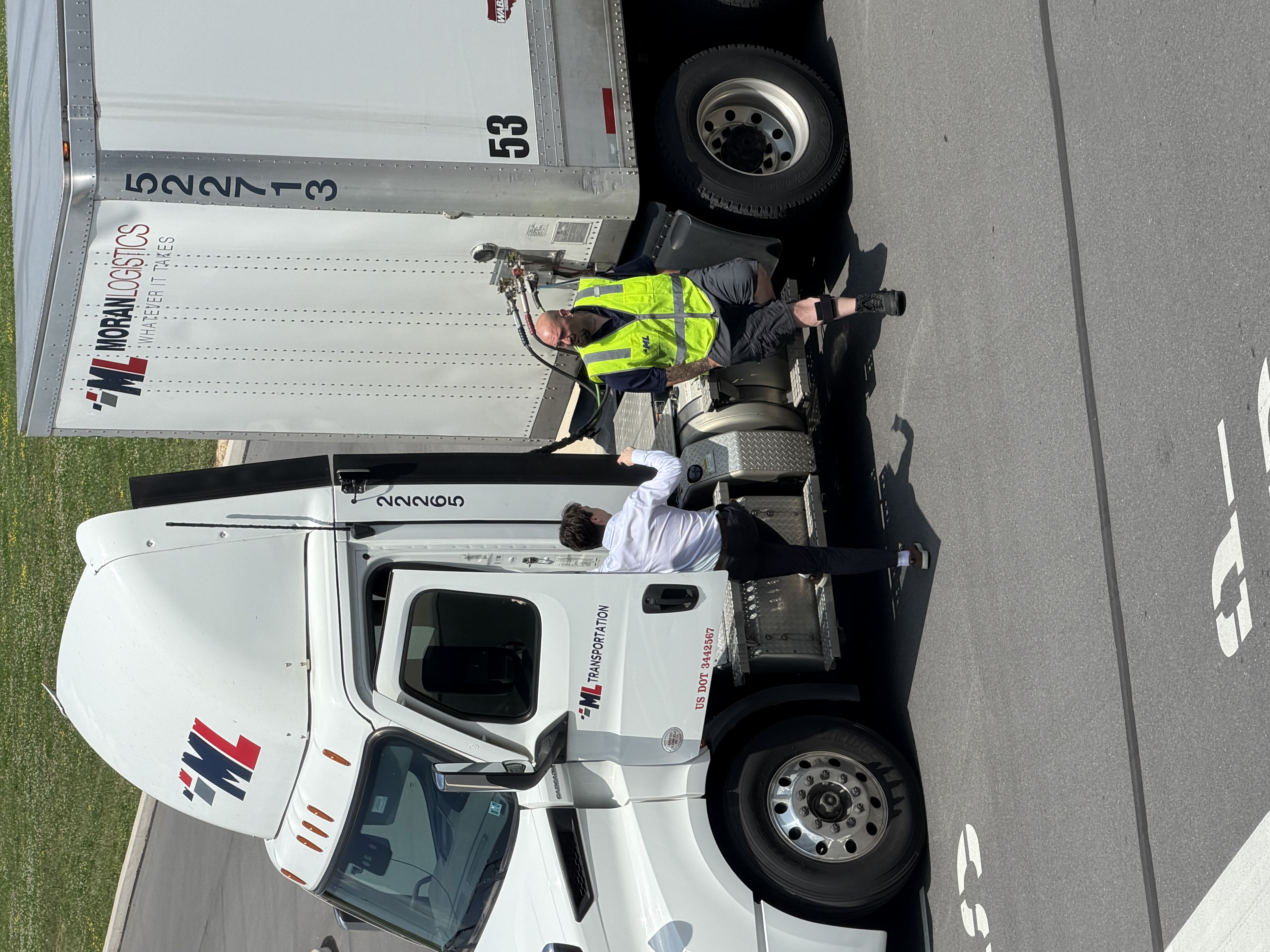 A driver and a member of the Movo team talking beside a tractor-trailer in the yard