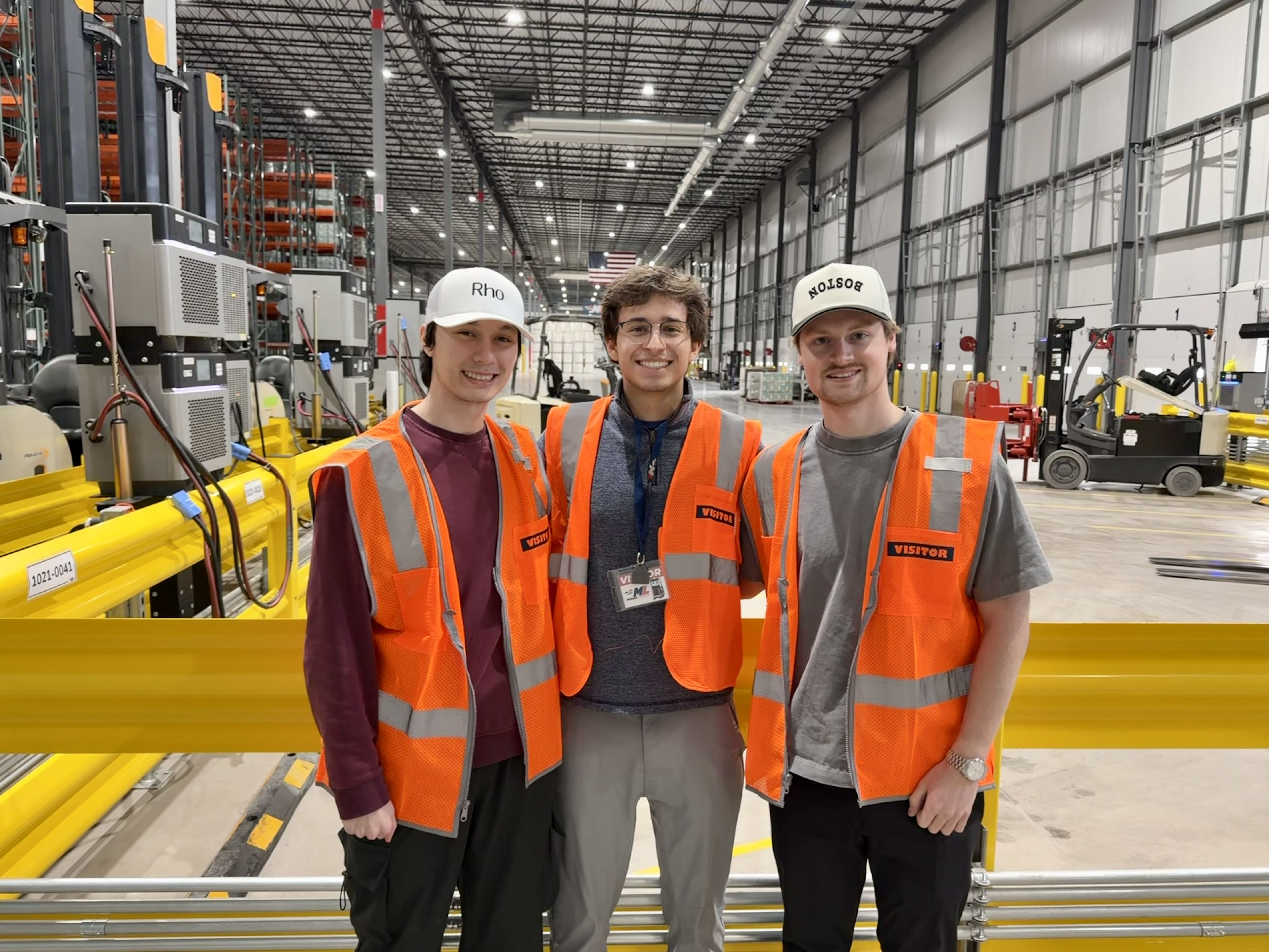 Three of the Movo team in visitor vests on a working warehouse floor