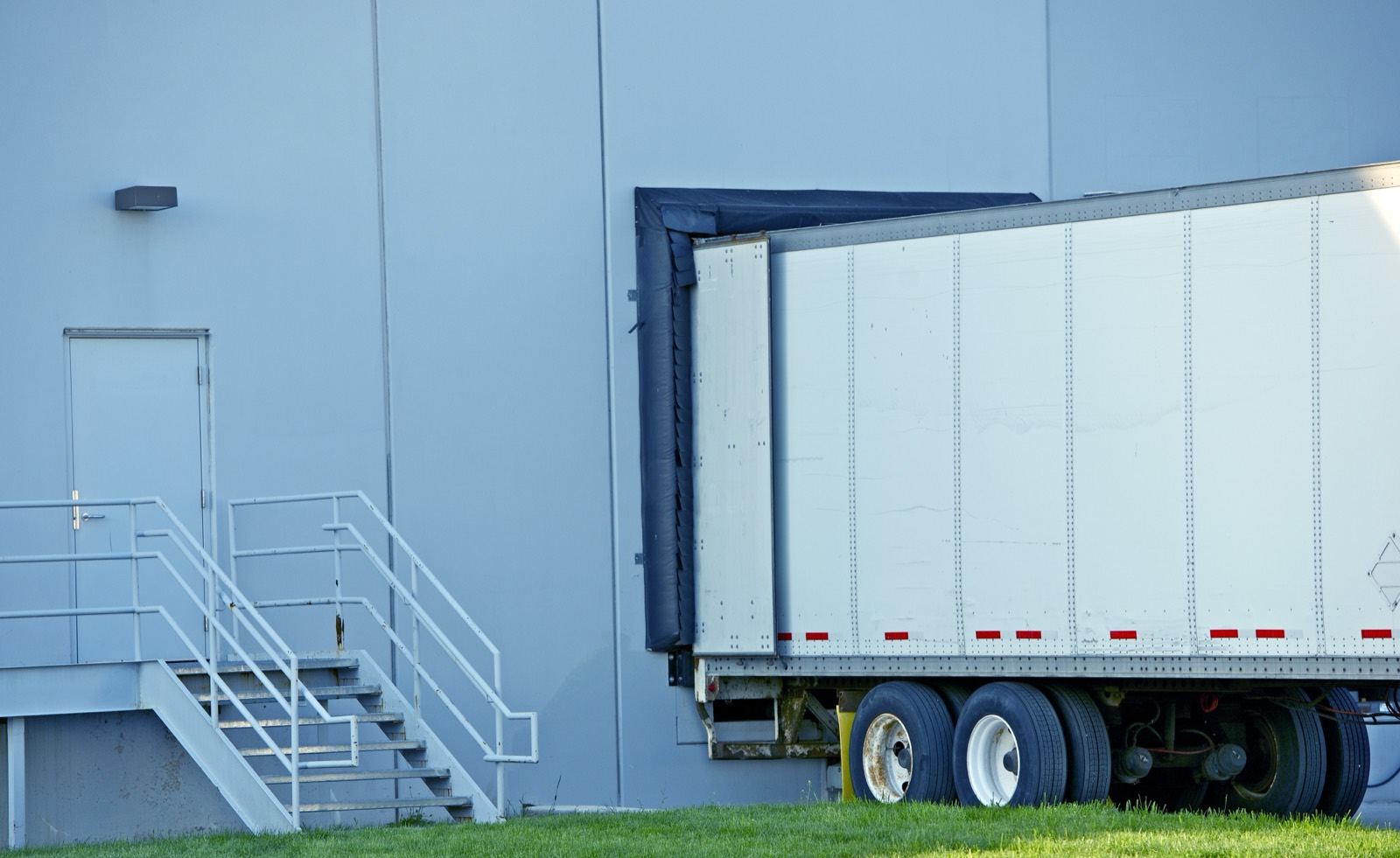 A trailer backed into a warehouse dock door, sealed against the building